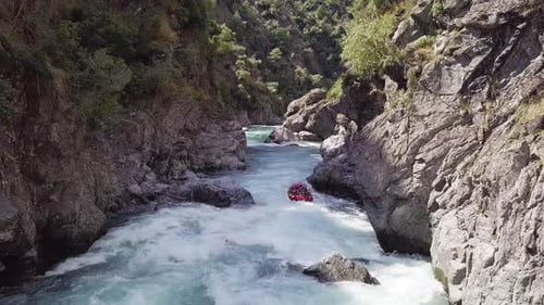 Menschen auf einer Wildwasser-Raftingfahrt beim Slamming am felsigen Flussufer in Neuseeland - Luftaufnahme