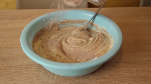 Adding Powder to Brown Cake Batter in Bowl