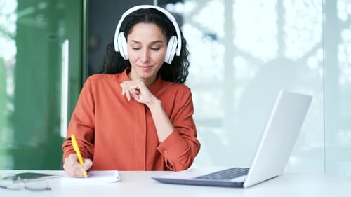 Woman Works at Desk with Laptop and Headphones