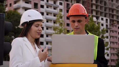 A Builder and an Architect with a Laptop are Standing at a Construction Site