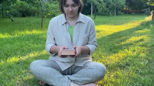 Woman Plays Small Musical Instrument Outdoor at Sunrise