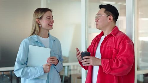 Koreanischer Mann genießt energisch eine Tasse Kaffee, während er drinnen mit einer Dame chattet