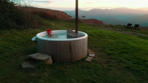 Drone Shot of Woman Lay in Steaming Wooden Hot Tub