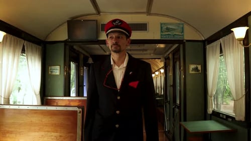 Un contrôleur de billets de chemin de fer avec chapeau rouge marche dans un vieux wagon-restaurant vintage vide d'un train à l'ancienne