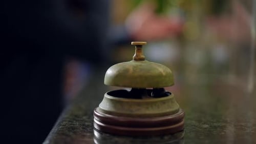 Closeup Female Hand Pressing Oldfashioned Hotel Bell on Reception Desk