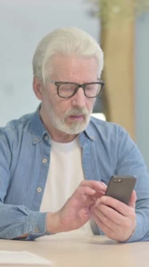 Old Man Using Smartphone in Office, vertical video