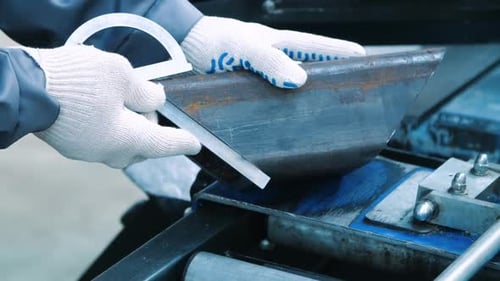 Metalworker measuring piece of metal at industrial workplace