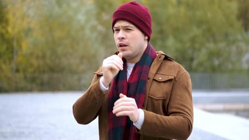 Young Man Coughing and Blowing Nose Outdoors