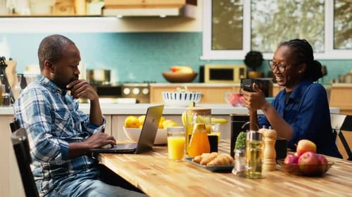 Man and Woman in Kitchen with Laptop and Phone