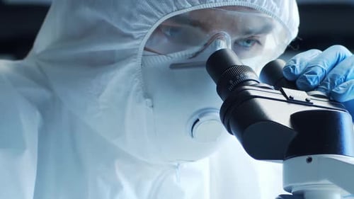 Adult in Protective Suit Using Microscope