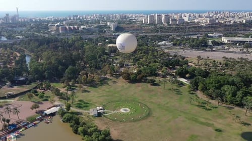 Aerial Shot Of Hot Air Balloon Descending Over Yarkon Park Against Sky In City