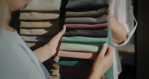 The Buyer Chooses the Fabric in the Textile Store the Seller Holds Samples with Multicolored Fabric