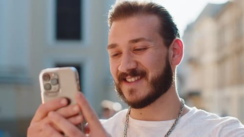 Young Man Use Smartphone Typing Text Messages Browsing Internet Finishing Work Looking at Camera