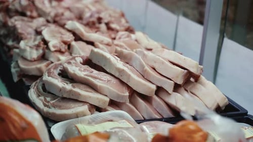 Trays of fresh raw pork chops on a tray in the butcher shop window.