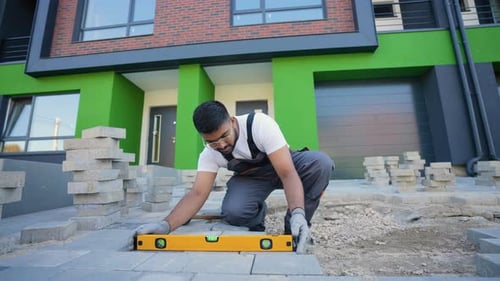 Skilled Tradesman Laying Paving Stones Outside