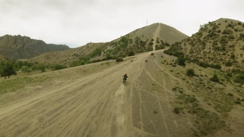 Motorcyclist Walkthroughs Track in Hilly Valley
