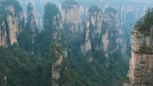 Misty Sandstone Pillars Rising Above Forested Mountains and Deep Valley Landscapein Zhangjiajie