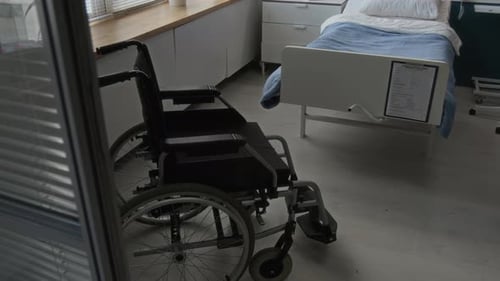 Hospital Room Corner Showing Black Wheelchair Positioned near Glass Partition