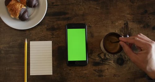 Green screen mobile. A man stirring the coffee with a teaspoon. Top view table with a coffee. Coffee