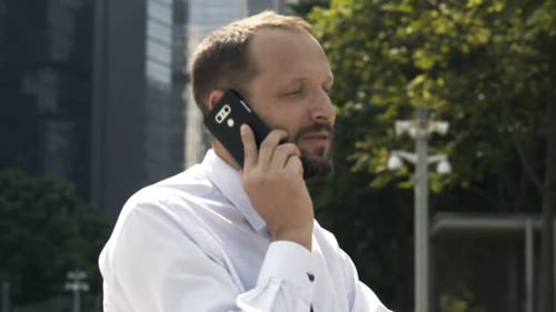 Young Businessman Talking on Cellphone Sitting in City 30s