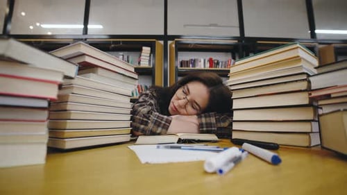 Tired Student Sleeping on Books in Library