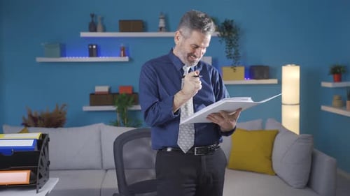 Fun and pleasant working mature businessman enjoys working in his home office.Fun and pleasant worki