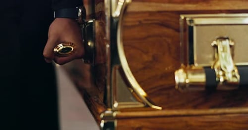 Hand Holding Ornate Wood and Gold Coffin