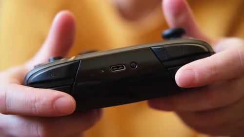 Hands Operate a Black Video Game Controller