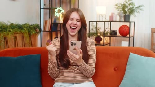 Excited Brunette Woman Celebrates Success on Mobile Phone