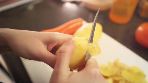Female hands peeling potatoes in the kitchen in slow motion