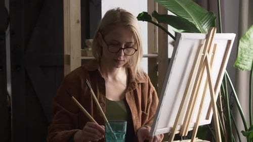 Une femme dessine sur un chevalet à la maison, pour soulager le stress