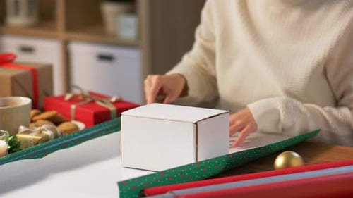 Woman Wrapping Gift at Table with Decorations