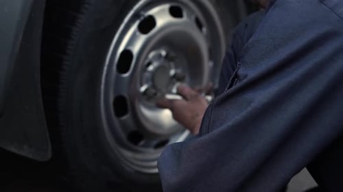 Mechanic Removing Car Tire in Urban Setting