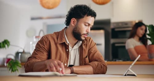 Man Using Tablet and Writing in Kitchen