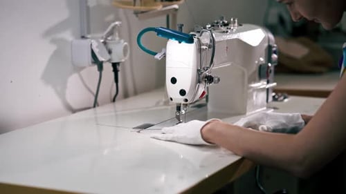 Nettoyeuse à sec professionnelle, une jeune fille ourle un patch sur un pull à l'aide d'une machine à coudre