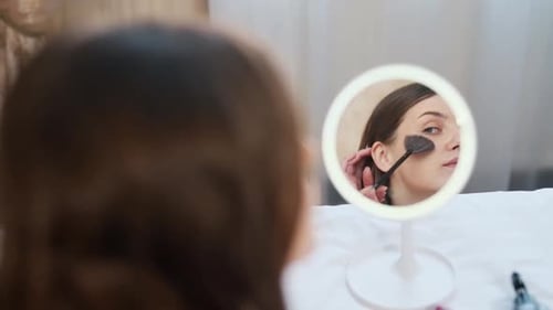 Woman Applying Makeup Using Mirror in Bedroom