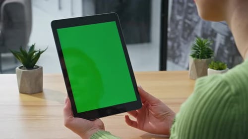 Woman Holding Tablet with Green Screen at Table