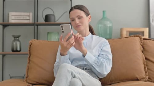 Woman Using Smartphone on Couch in Home