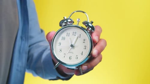 Business Man Shows the Time on the Alarm Clock 1105 O'clock Yellow Background
