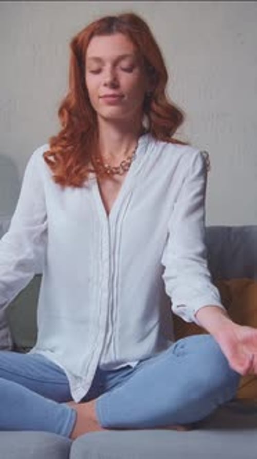 Woman Meditating Peacefully on Couch at Home
