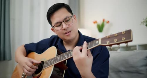 Man Playing Acoustic Guitar in Living Room