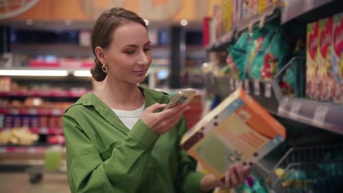 Woman Using Smartphone for Checking Product Information in Supermarket