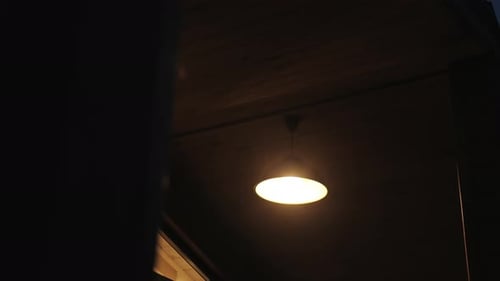 Alone Electric Lamp Gives Warm Light on Outdoor Terrace of Wooden House in the Evening Cozy