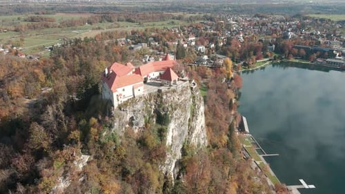 Aerial shot of a castle near a lake perched on a high rock in the mountains of Slovenia, Lake Bled.