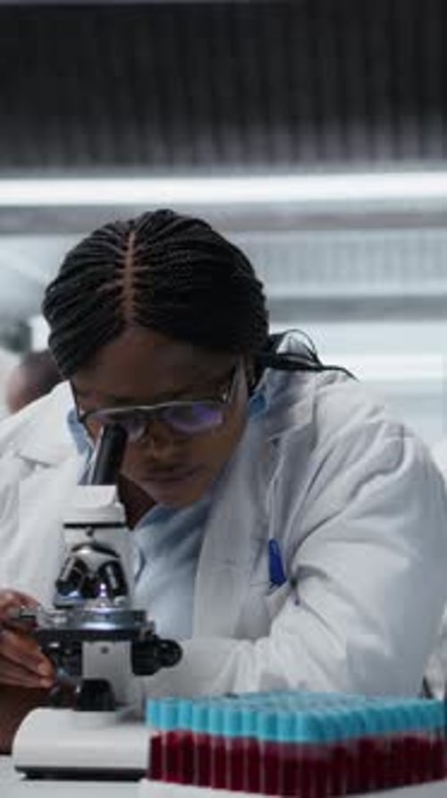 Woman Scientist Using Microscope in Laboratory Setting
