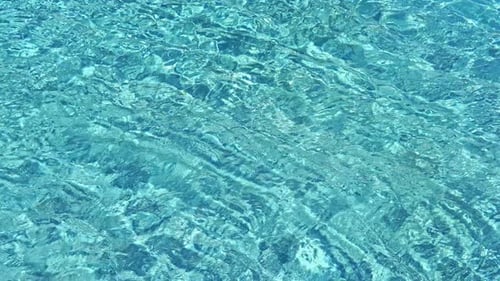 Kristallklares azurblaues Wasser eines Schwimmbeckens mit langsamen Wellen auf seiner Oberfläche.