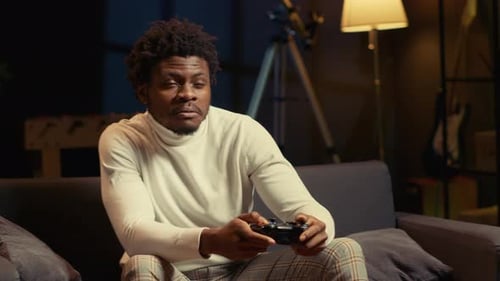 Man Plays Video Game on Sofa at Home