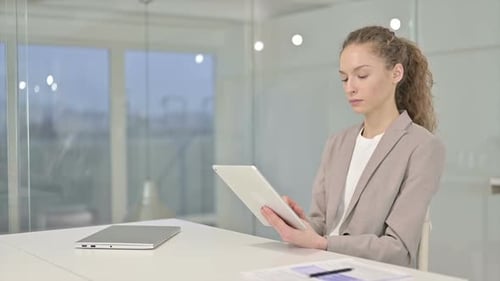 Hardworking Young Businesswoman using Tablet in Modern Office