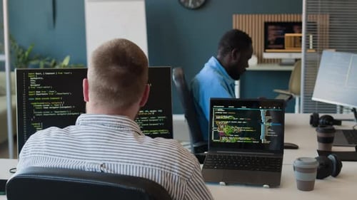 Man Working On Codes Using Two Computers