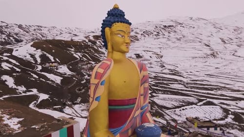Close-up view of a golden Buddha statue seated in meditation , snow background